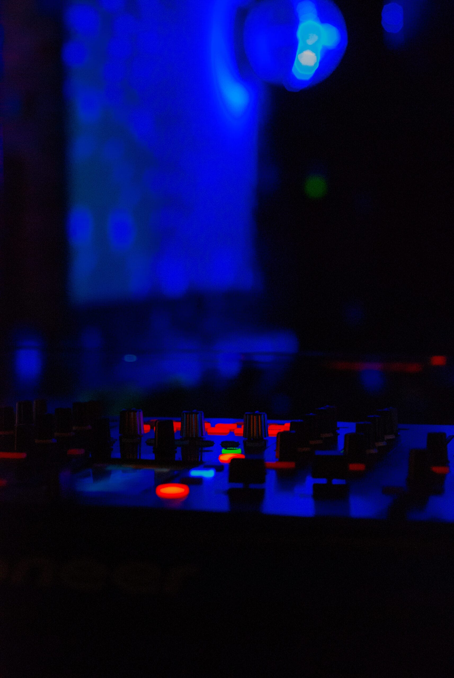 Dj mixer with headphones at nightclub. In the background laser light show